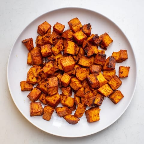 Golden roasted sweet potatoes with crisp edges, sprinkled with smoked paprika and cumin for a smoky aroma.