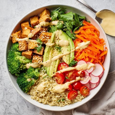A hearty Buddha Bowl with chicken, quinoa, and colorful fresh veggies, topped with toasted sesame seeds and a bright lemon-tahini sauce.