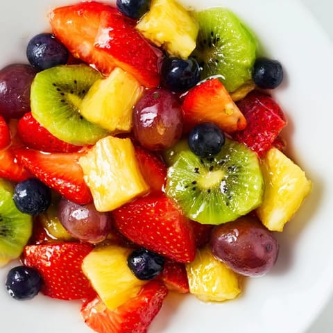 Summer Fruit Salad lightly tossed in citrus syrup, garnished with fresh mint leaves.