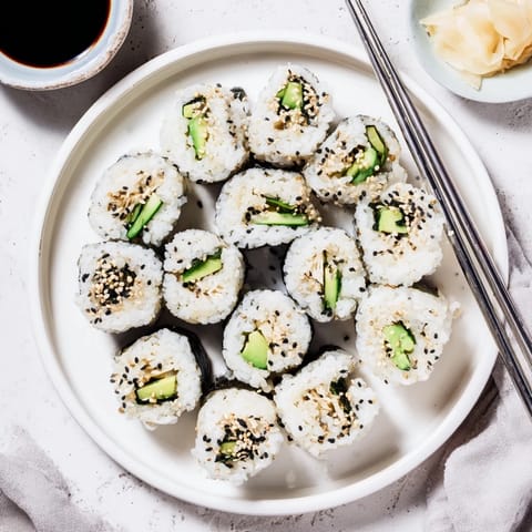 Homemade California Roll on a plate with soy sauce, wasabi, and pickled ginger, classic serving style.