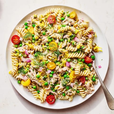 Close-up of Lemony Tuna Pasta Salad with flaked tuna, red onion, and a glistening lemon-herb dressing, perfect for picnics.