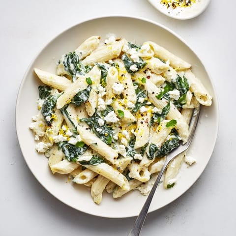 The finished Creamy Feta Spinach Pasta dish garnished with lemon zest and fresh basil, ready to serve for dinner.  