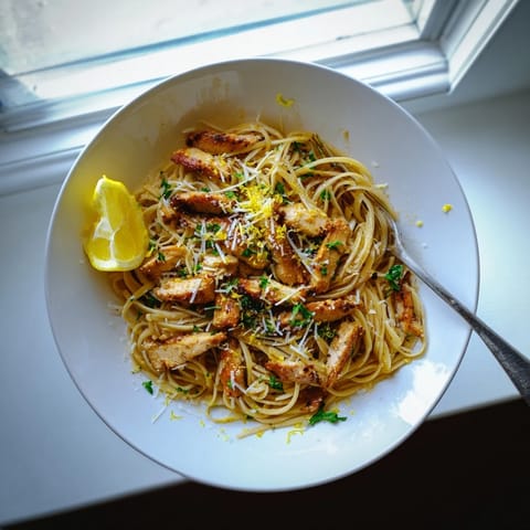 Freshly grated Parmesan and lemon wedges frame this skillet of Brown Butter Lemon Chicken Pasta, highlighting its glossy, herb-flecked sauce.