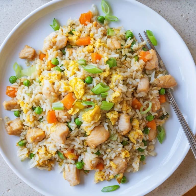 A close-up of homemade Chicken Fried Rice with diced carrots, onions, and green onions tossed with tender chicken and seasoned perfectly.
