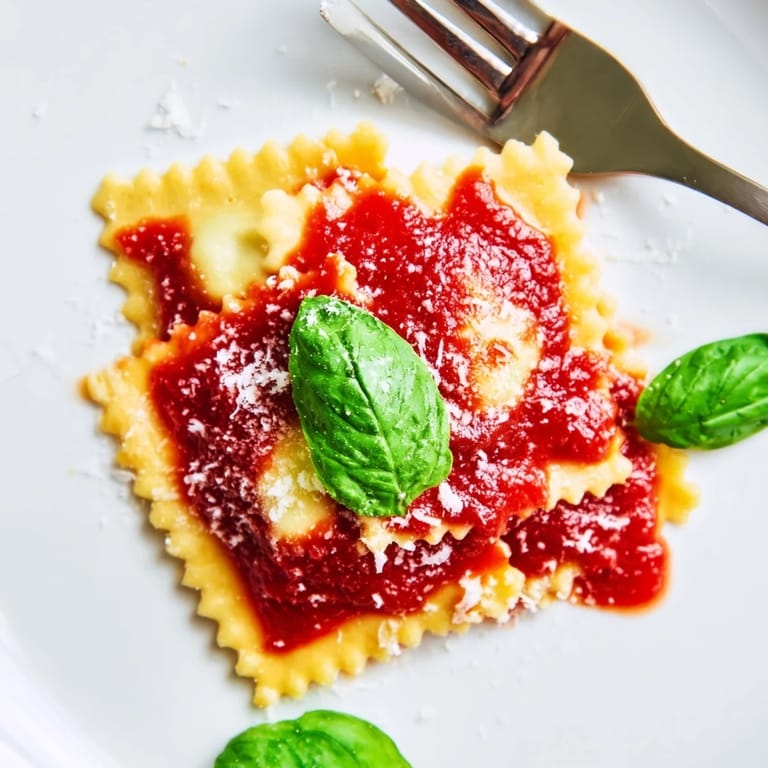 A close view of spinach ricotta ravioli topped with marinara sauce and a sprinkle of Parmesan.