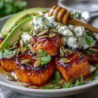 Golden roasted sweet potato cubes with crispy edges topped with creamy avocado and cottage cheese in a Hot Honey Sweet Potato Bowl.