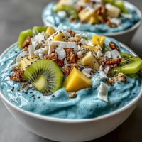 Vibrant blue spirulina smoothie bowl topped with fresh tropical fruit, perfectly blended.